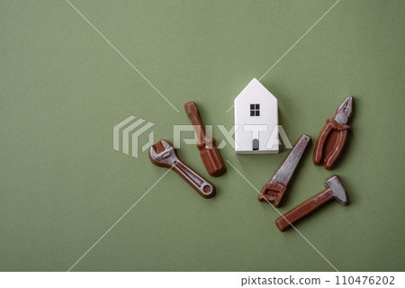 Repair or home improvement tools and a house model on a plain background Repair or home improvement tools and a house model on a plain background 110476202