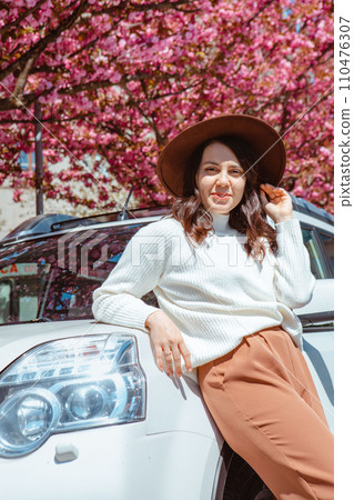stylish smiling beautiful woman standing near car blooming sakura tree on background stylish smiling beautiful woman standing near car blooming sakura tree on background 110476307