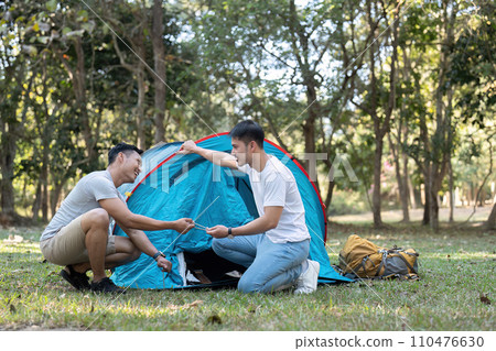 Happy Asian male gay couple on camping together in a forest. romantic vocation trip. lgbt concept Happy Asian male gay couple on camping together in a forest. romantic vocation trip. lgbt concept 110476630