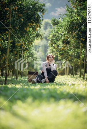 A happy woman farmer is resting in orchard or orange farm. 110476684