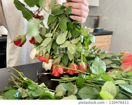 Female hands make a beautiful bouquet of red and white small roses Female hands make a beautiful bouquet of red and white small roses 110476811