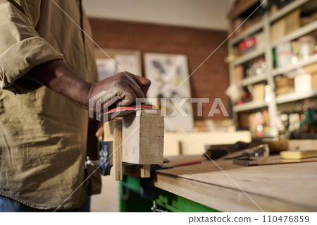 Close up of African American carpenter polishing wooden board and building furniture in workshop Close up of African American carpenter polishing wooden board and building furniture in workshop 110476859