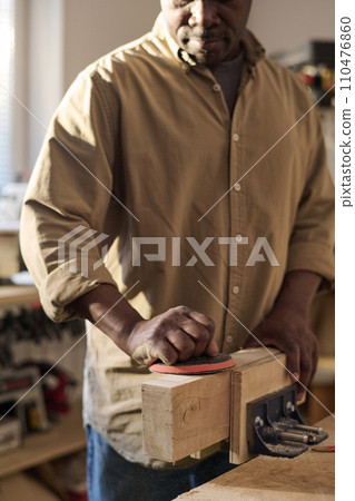 Vertical closeup of senior carpenter polishing wooden board while building furniture in workshop Vertical closeup of senior carpenter polishing wooden board while building furniture in workshop 110476860