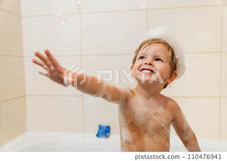 Cute little boy having fun in the bath with foam and bubbles Cute little boy having fun in the bath with foam and bubbles 110476941