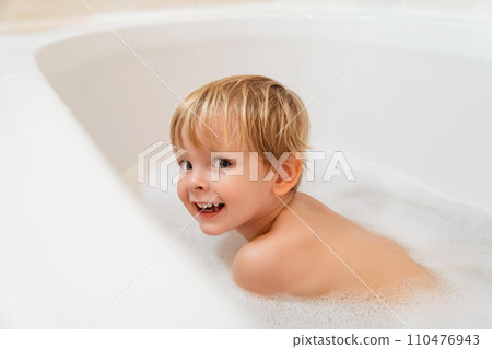 Portrait of a cute little boy taking a bath in bathtub at home. 110476943