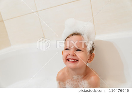 Cute baby taking a bath in the bathtub with foam and laughing Cute baby taking a bath in the bathtub with foam and laughing 110476946