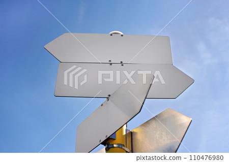 Empty metal tables shaped like arrows against blue sky - add your text 110476980