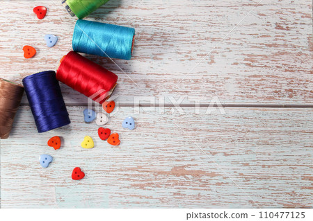 A set of colored threads for sewing clothes, on a wooden background 110477125