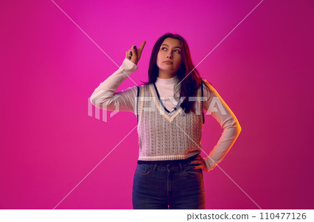 Lost in Thought. Portrait of young woman looking away with focused and contemplative expression, as if she's immersed in her thoughts. 110477126