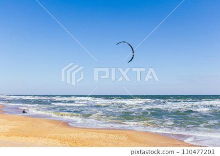 Kite surfing on the beach. Active lifestyle. Extreme sports concept. Man in wetsuit with kite board at seaside. Summertime active sport. Adrenaline and freedom. Surfer on aerial seascape background. Kite surfing on the beach. Active lifestyle. Extreme sports concept. Man in wetsuit with kite board at seaside. Summertime active sport. Adrenaline and freedom. Surfer on aerial seascape background. 110477201