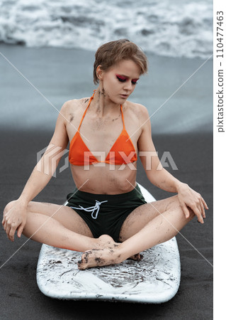 Woman practicing yoga on surfboard with eyes closed relaxing and enjoying moment of mindfulness 110477463