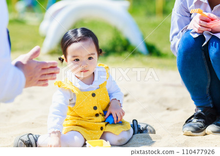 Parent and child playing in the sand at the park Parent and child playing in the sand at the park 110477926