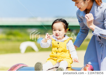 Infant and mom playing on a slide in the park Infant and mom playing on a slide in the park 110478056