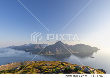 Gentle midnight sun lights Lofoten's mountains and ocean from Offersoykammen view 110478209