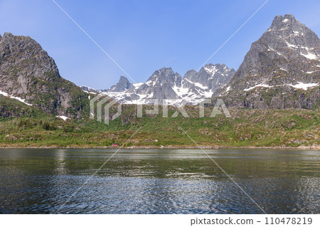 A classic rorbu softens the rugged grandeur of Lofoten's mountainside fjord. 110478219