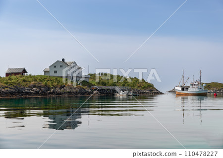 Rorbu cabins and a fishing vessel reflect in Lofoten's tranquil waters Rorbu cabins and a fishing vessel reflect in Lofoten's tranquil waters 110478227