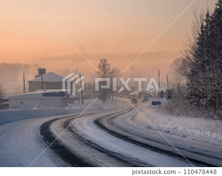 Frosty morning sunrise winter snow-covered highway through Cherdyn village 110478448