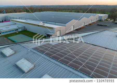 Aerial view of solar power plant with blue photovoltaic panels mounted on industrial building roof for producing green ecological electricity. Production of sustainable energy concept Aerial view of solar power plant with blue photovoltaic panels mounted on industrial building roof for producing green ecological electricity. Production of sustainable energy concept 110478593