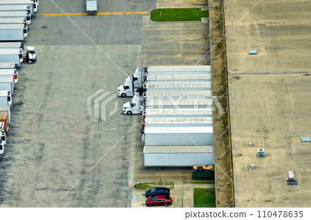 Aerial view of large commercial loading bay with many delivery trucks unloading and uploading retail goods for nationwide distribution. Global economy concept 110478635