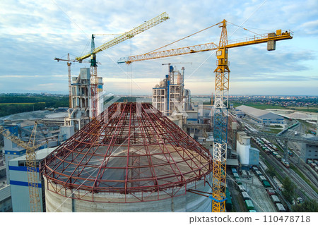 Aerial view of cement factory under construction with high concrete plant structure and tower cranes at industrial production area. Manufacture and global industry concept. 110478718