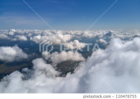 Aerial view from airplane window at high altitude of earth covered with white puffy cumulus clouds. 110478755