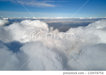 Aerial view from airplane window at high altitude of earth covered with puffy cumulus clouds forming before rainstorm 110478758