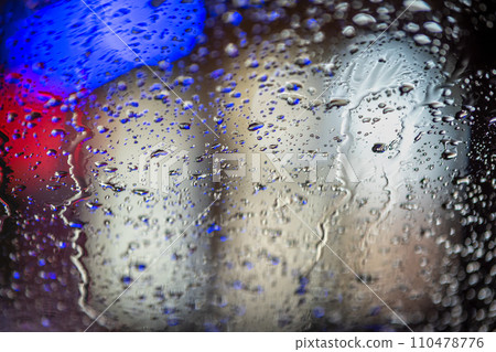 Abstract colorful background of glass surface with water drops and blurred city lights. 110478776