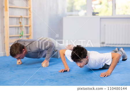 Father and son train abdominal muscles in gym - perform plank exercise Father and son train abdominal muscles in gym - perform plank exercise 110480144