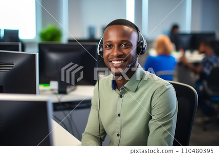 A smiling African-American man with headphones and a microphone in a call center 110480395