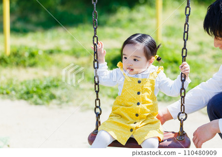 Cute little girl playing with toddler and family in the park 110480909