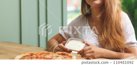 A girl dips a slice of pizza in sauce 110481092