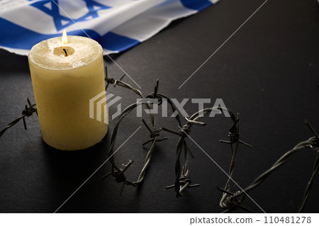 Flag of Israel, barbed wire and burning candle on black background. Holocaust memory day 110481278