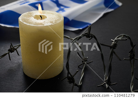 Flag of Israel, barbed wire and burning candle on black background. Holocaust memory day 110481279