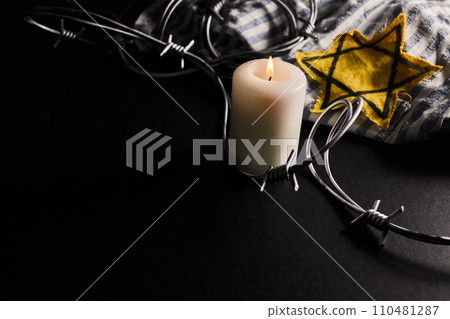 Holocaust memory day. Arbed wire and burning candle on black background 110481287