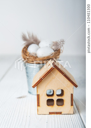 Happy Easter greeting card. Miniature wooden house. Rabbits, colorful eggs, spring flowers with tag for text Happy Easter greeting card. Miniature wooden house. Rabbits, colorful eggs, spring flowers with tag for text 110481300