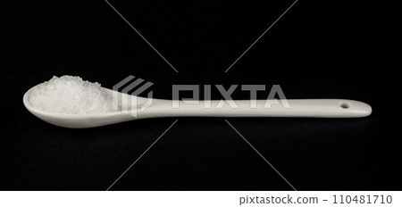 A spoonful of white salt on a black background. Sea food salt. 110481710