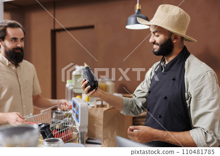 Middle eastern vendor talking to customer and selling homegrown products at local store. Shopkeeper helping client to choose locally grown produce, explaining health benefits of fresh food. Middle eastern vendor talking to customer and selling homegrown products at local store. Shopkeeper helping client to choose locally grown produce, explaining health benefits of fresh food. 110481785