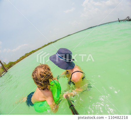 Mother and son enjoy a turquoise lake in Mexico 110482218