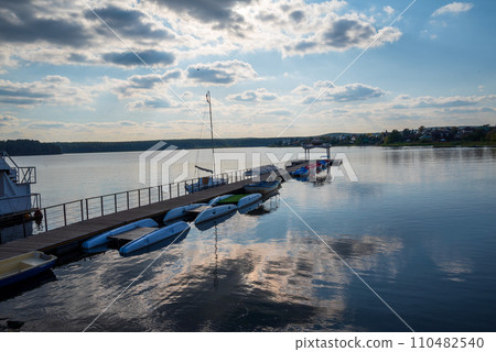pier with boats on the lake on the background of a sunset sky with clouds pier with boats on the lake on the background of a sunset sky with clouds 110482540