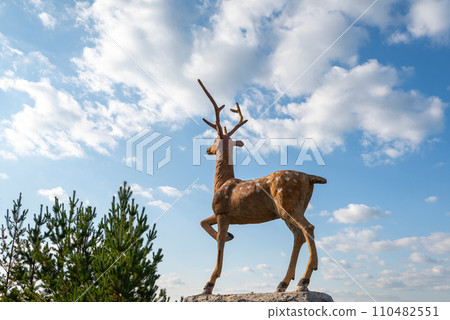 deer sideways on a background of blue sky with clouds and forests deer sideways on a background of blue sky with clouds and forests 110482551