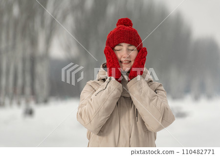 Winter portrait of happy girl on snowy nature background. Young woman in fashionable winter clothes on walk 110482771