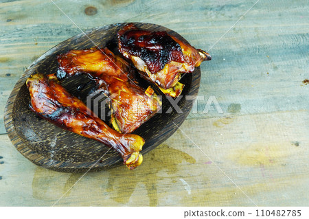A close up photo of a halved and grilled chicken on a rustic wooden platter A close up photo of a halved and grilled chicken on a rustic wooden platter 110482785