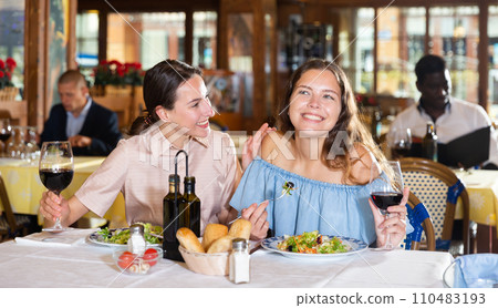 Two best friends have fun talking at a table in restaurant 110483193