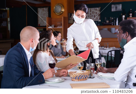 female waitress in mask taking order from female and male customers in cafe female waitress in mask taking order from female and male customers in cafe 110483206