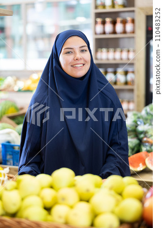 Smiling young muslim female shopper standing in grocery store Smiling young muslim female shopper standing in grocery store 110483252
