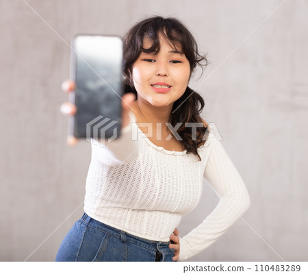 Smiling young girl holding mobile phone Smiling young girl holding mobile phone 110483289