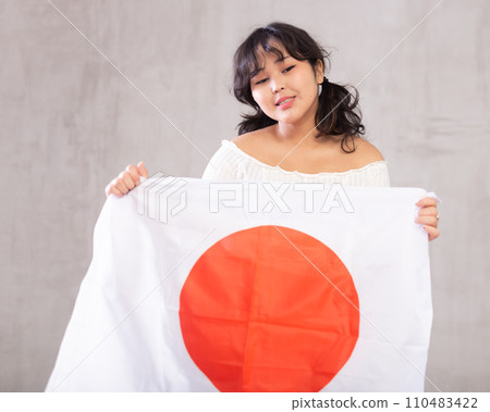 Smiling young girl holding Japan flag Smiling young girl holding Japan flag 110483422
