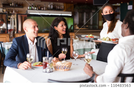 Waitress in protective mask bringing ordered meals to guests Waitress in protective mask bringing ordered meals to guests 110483563
