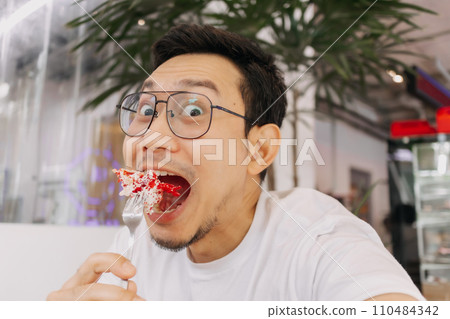 Funny happy face of man eating and putting cake into his mouth. Funny happy face of man eating and putting cake into his mouth. 110484342
