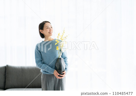 一位 30 多歲的女士用鮮花裝飾她的房間 110485477